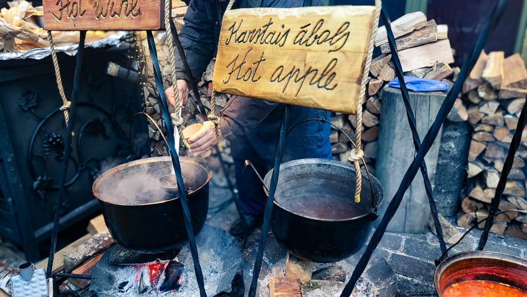 Hot drinks being warmed in cauldrons over real fire at Riga Christmas Market.